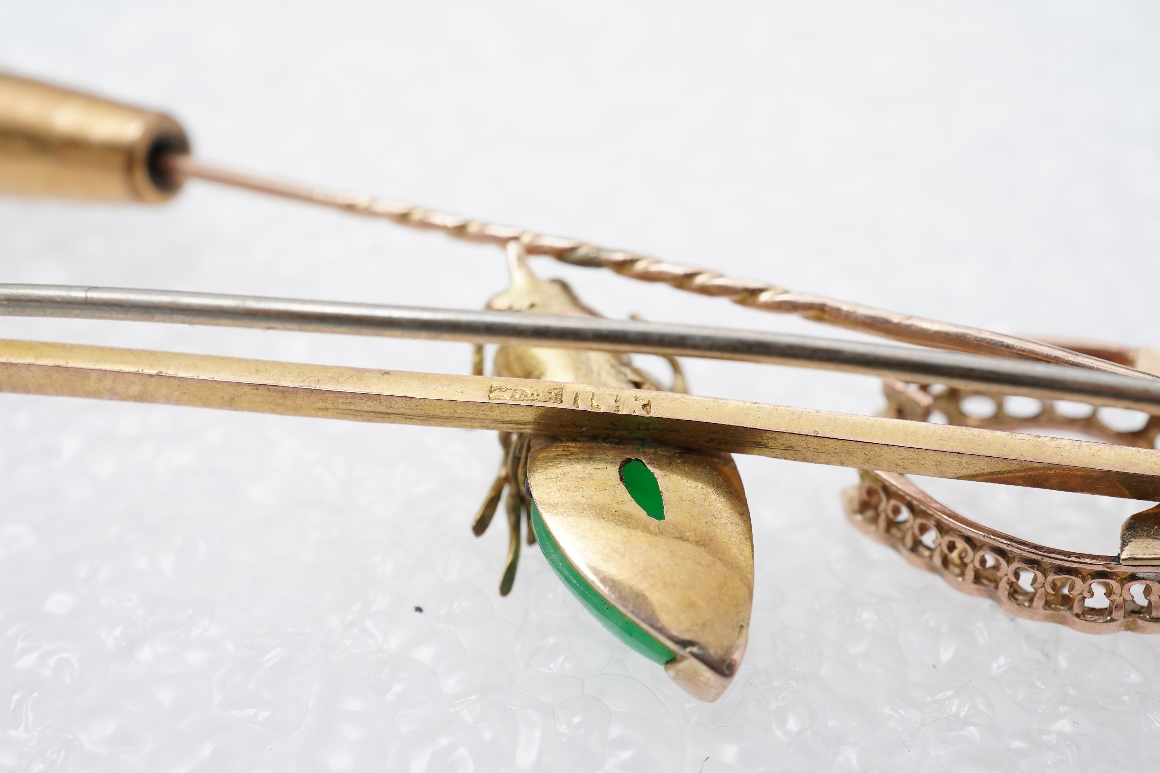 Two stick pins and a jadeite bar brooch, comprising: a bar brooch centring on an insect set with a pear-shape jadeite cabochon and a pearl, mounted in gold, length 7.5cm, stamped 14K, base metal pin; a stick pin capped w